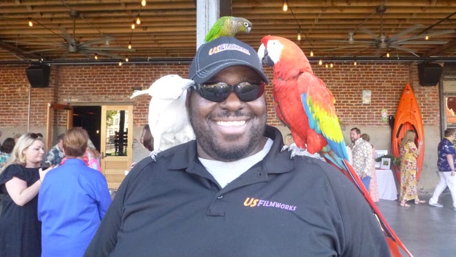 Among those attending the Sertoma Center’s "Taste of the Tropics" auction and dinner were birds from Parrott Mountain. Here guest Tre Scott shows off several of the colorful parrots there for the evening.