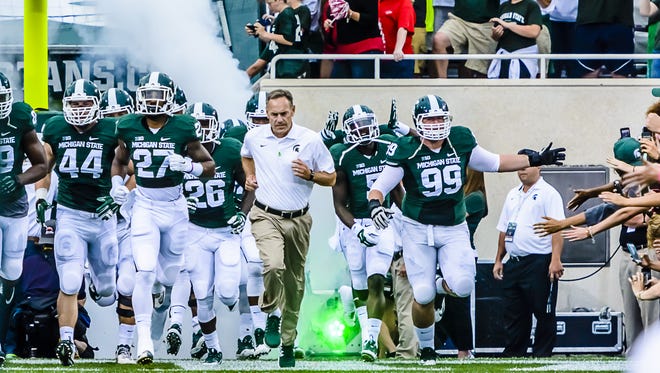 MSU Football Head Coach Mark Dantonio (center) leads his team onto the field for the first time in the 2014 season prior to the Spartans' game with Jacksonville State Friday August 29, 2014 in East Lansing.  KEVIN W. FOWLER PHOTO
