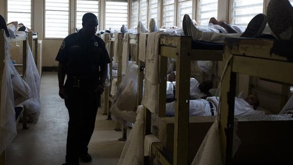 Corrections officer J. Spears walks through the sleeping are for inmates coming through intake at Kilby Corrections Facility in Montgomery, Ala., on Friday, Sept. 4, 2015. The facility is currently at 301 percent it's intended capacity. Kilby is currently housing 1,448 inmates and was designed for 440.