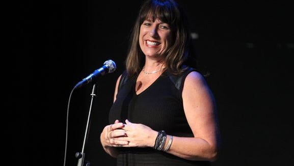 Karina Bland, wearing a sleeveless dress, while speaking at a work-related event.