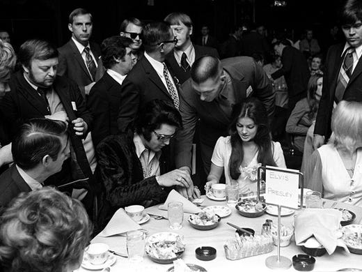 Elvis Presley signs autographs for fans during a luncheon at the Holiday Inn Rivermont in 1971. Presley was being honored by the Jaycees as one of the Outstanding Young Men In America. Priscilla Presley is seated by him. Seated on Elvis' other side is William N. Morris, former sheriff of Shelby County.