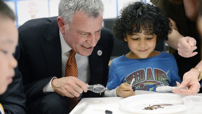In this April 3 file photo, New York Mayor Bill de Blasio works on a science project with prekindergarten pupil Justin De La Cruz during a visit to P.S.1 in New York. Now that the mayor has secured $300 million to put 4-year-olds in school, his administration must quickly find enough good teachers and classrooms to offer full-day prekindergarten to 53,000 children by September and another 20,000 by September 2015.