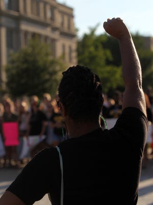 Lisa Covington raises her fist during a rally against police brutality at the Pentacrest on Thursday, July 14, 2016. 