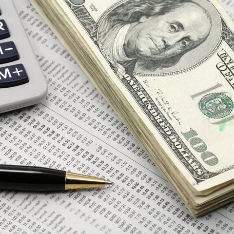 A neat stack of cash, a calculator, and a pen lyin