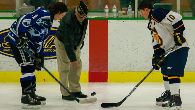 Brockport senior captain Mitchell Henshaw, left, and Spencerport senior captain Max Moran, right, during the ceremonial puck drop by veteran Roy McCloud at Brockport’s annual Military Appreciation Game.