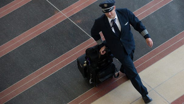 An airline pilot walks through the terminal at...