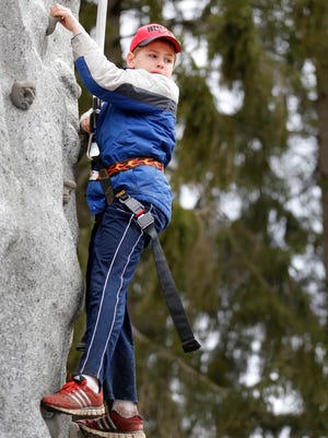 Jamie Kosten, 9, of Fairport’s Scout Troop 362, looks down from a temporary rock wall at Potter Park in Fairport on Saturday.