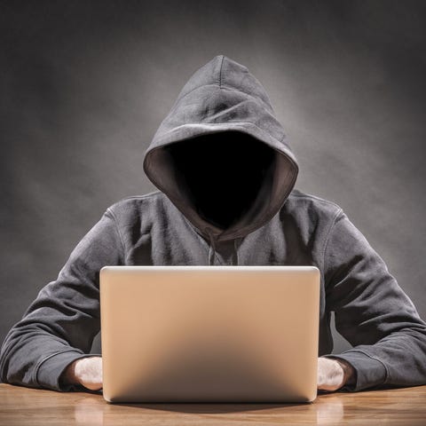 Faceless person in hoodie at laptop