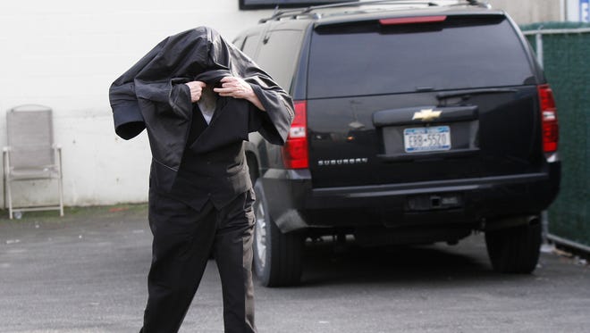 Peretz Klein, owner of Hashomer Alarm, Inc. is seen leaving his office at 29 Robert Pitt Drive in Spring Valley, cloaked under his jacket as federal agents collect evidence on Wednesday, March 16, 2016.