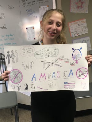 Angela Demas, 14, with the sign she took to Okemos High School after Tuesday's election.