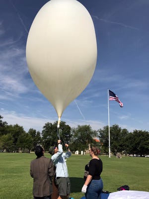 Paulo Oemig, center, New Mexico Space Grant Consortium research scientist, holds a high-altitude balloon during a test on June 20, 2017 at the New Mexico State University Horseshoe while Krishna Kota, left, mechanical engineering assistant professor, and Norann Calhoun, chemical engineering senior, assist. A high-altitude balloon launch was part of the NASA-sponsored Eclipse Ballooning Project, which was held during the total solar eclipse earlier this month.