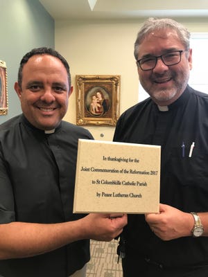Father Lorenzo Gonzalez, left, and Pastor Walter Still with plaque for Reformation tree that the churches are planting to commemorate the 500th anniversary.