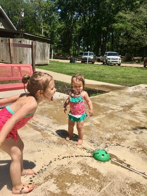 Sisters Avery and Marie Guidry play at the splash pad at Lake Bruin State Park in St. Joseph.