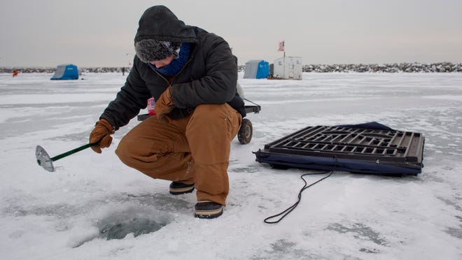 Brad Thompson, of Brown City, scoops chunks of ice as he prepares a fishing hole Saturday on Lexington State Harbor.