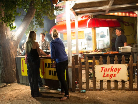 Campers buy late night food at a barbecue vendor in