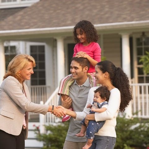 A family with children shakes hands with a real es