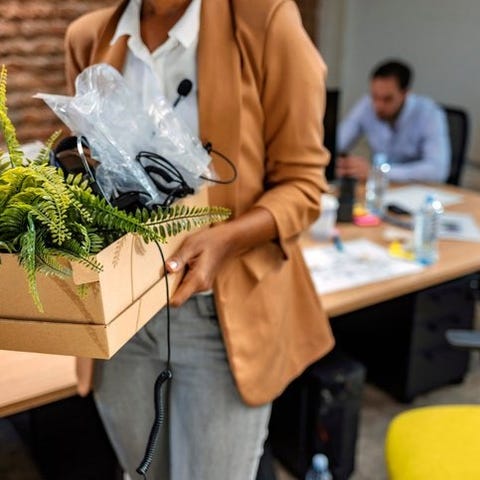 A woman walking out of an office with a cardboard 