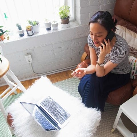 A woman sitting on her couch at home making a phon