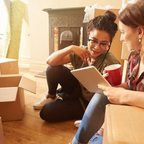 Two women sitting on the floor between moving boxe