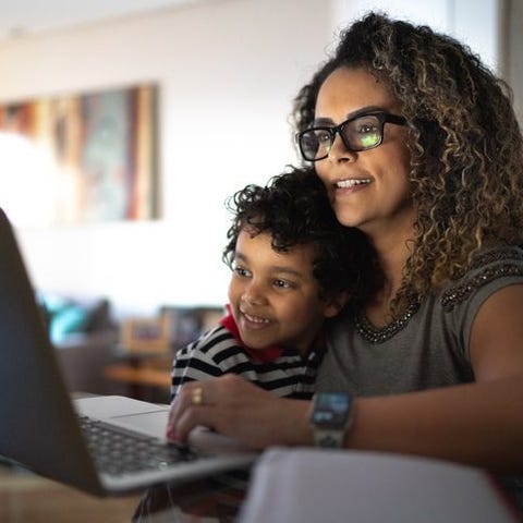 A parent and child smile as they look at a laptop 