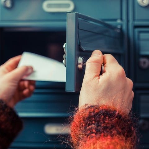 A woman's hands opening a mailbox and pulling out 