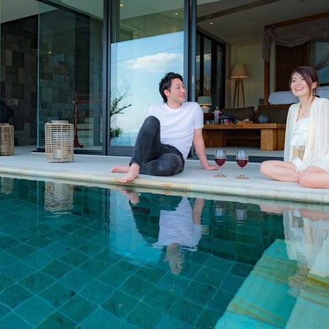 A man and woman sitting at the edge of a pool outs