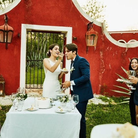 A bride feeding cake to a her groom at an outdoor 