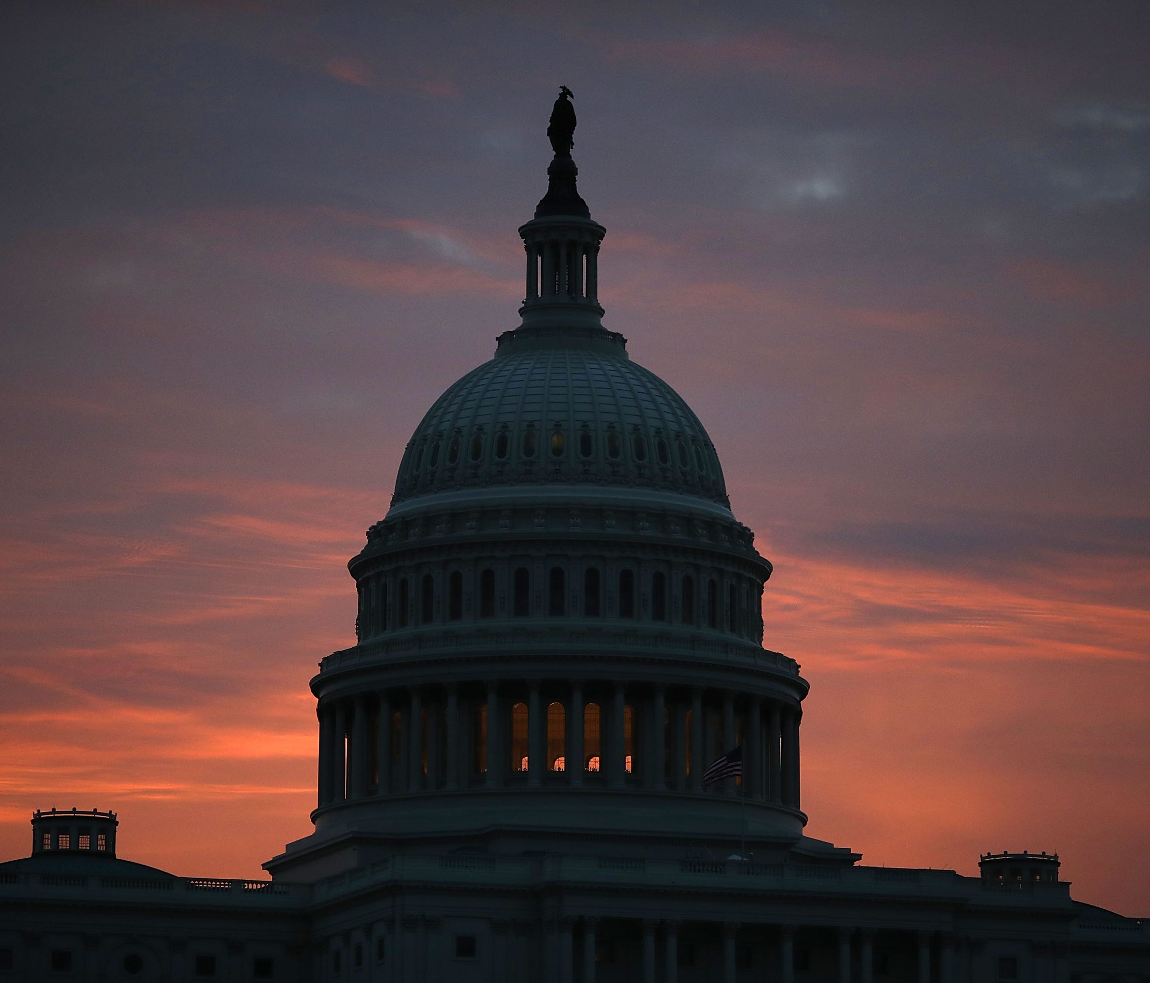 The sun lights up the sky behind the U.S. Capitol Building.