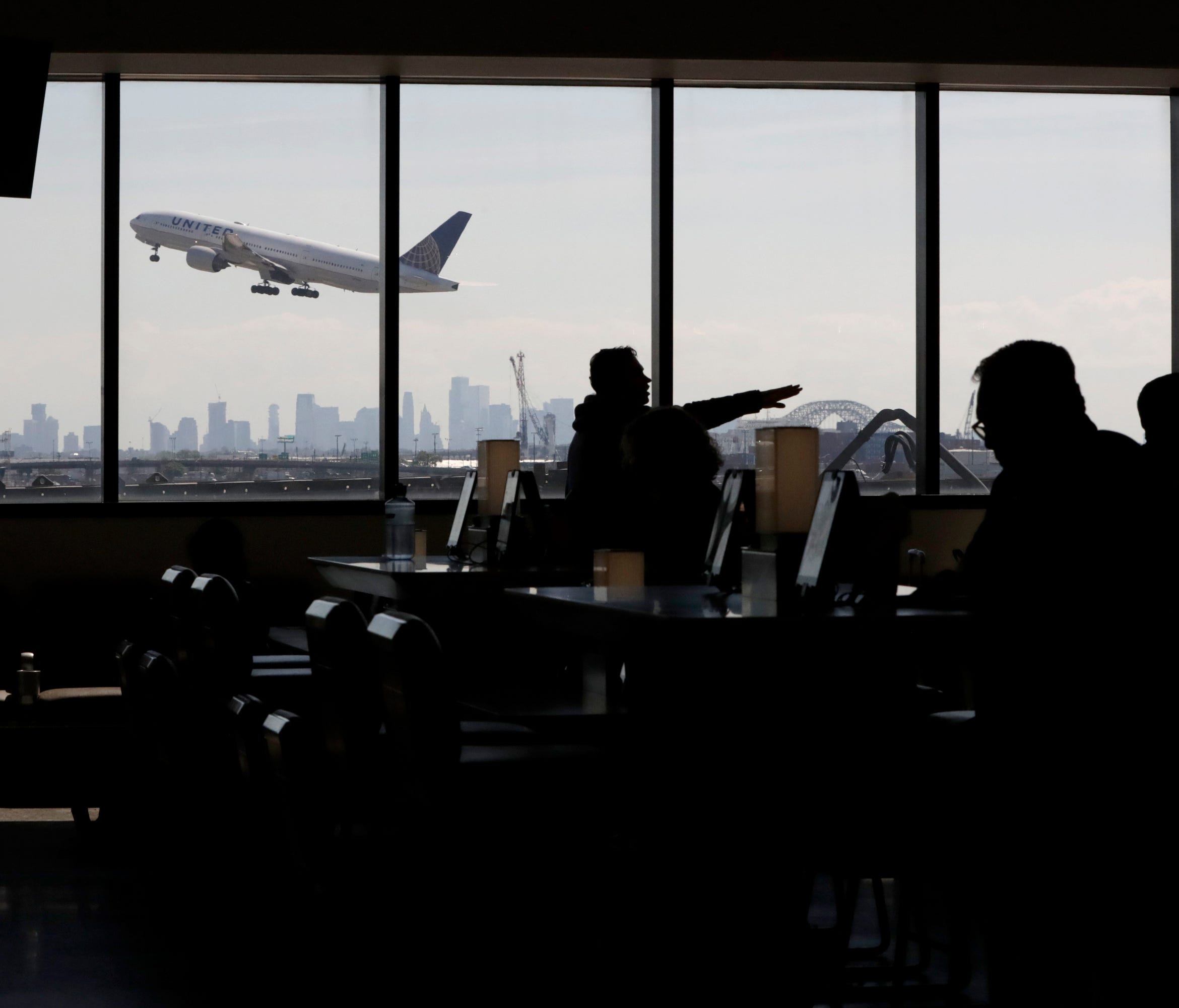 A United Airlines commercial jet takes off as travelers sit at a gate in Terminal C of Newark Liberty International Airport on July 18, 2018, in Newark, N.J.
