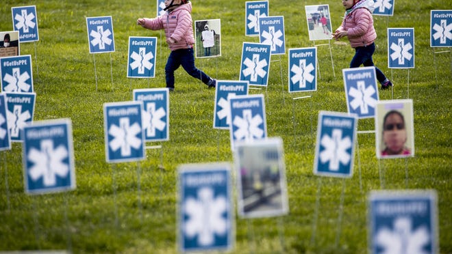 File - Children run though a thousand signs made by the advocacy group MoveOn along with other organizations that read #GetUsPPE, along images of health care workers, a call for personal protective equipment for health care workers during the coronavirus outbreak, on the West Lawn of the U.S. Capitol, Friday, April 17, 2020, in Washington.