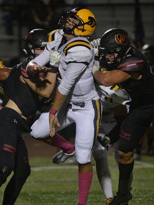Newbury Park quarterback Cameron Rising, center, gets the pass off right before Oaks Christian's Jackson Lenthall, left, and Bo Calvert hit him during Friday night's game at Oaks Christian School. The Lions won, 48-0.