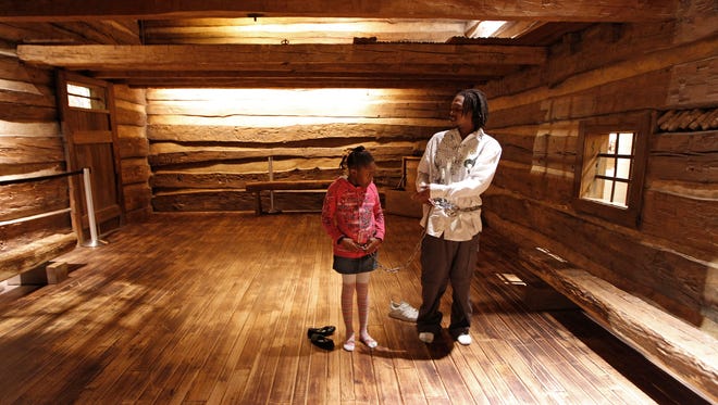 Robert Cooley of College Hill teaches his daughter Cree Rayford, 7, of Avondale the history of the slave house and why chains
were used at the National Underground Railroad Freedom Center.