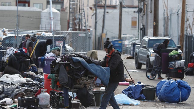 Homeless people clear their belongings of from a camp near the Denver Rescue Mission, Tuesday, March 8, 2016, in Denver. The city has spent months urging the campers to move into shelters and get rid of makeshift structures that officials say pose a health hazard.