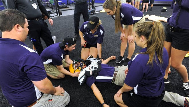 Nellie Doneva/Reporter-News Athletic training students work on a 'patient' portrayed by classmate Jeremiah Slaughter during an emergency care training workshop Tuesday at Hardin-Simmons University. The workshop focused on spinal injuries, heat illnesses and cardiac arrest in football players.