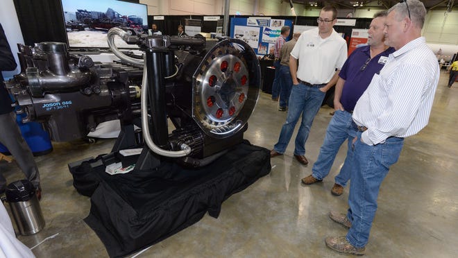 Convention goers look over a 500HP well service pump on display at Jason Oil and Gas tEquipment booth in the Shreveport Convention Center during the first day of the Ark-La-Tex Oilfield Expo. The expo continues Thursday and is the first time being held in Shreveport.
