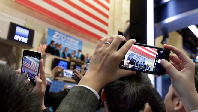 People on the floor of the New York Stock Exchange use their mobile phones to photograph as ZTO Express prepares to ring the opening bell for their IPO, Thursday, Oct. 27, 2016.