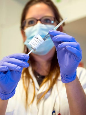 A nurse in Switzerland holds a dose of experimental vaccine developed at the National Institutes of Health.