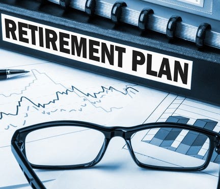 Binder marked Retirement Plan on table with glasses, pen, and paper with charts on it.