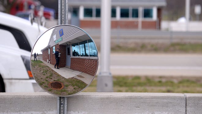 Michigan State Police Motor Carrier Officer Michael Patterson is seen reflected in a mirror as he walks into the Grass Lake weigh station after speaking with a trucker on April 22. Patterson had the driver pull the truck around to the inspection area after noticing he may have had a visual imparement on the windsheild. The driver left with a verbal warning.
