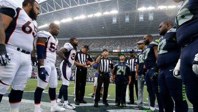 Referee Walt Anderson flips the coin at the start of a preseason NFL football game between the Seattle Seahawks and the Denver Broncos, Friday, Aug. 14, 2015, in Seattle.