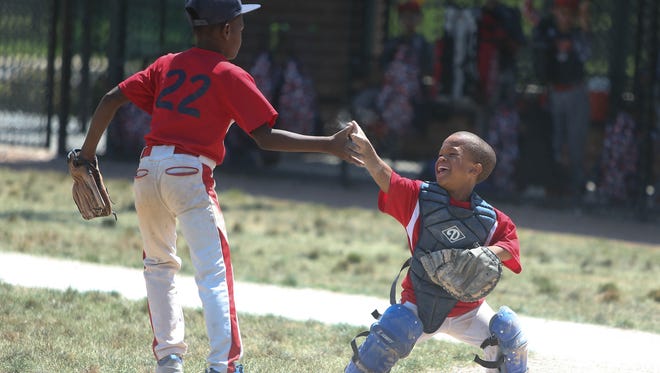 Trey Banks a catcher for the Detroit Braves ten and under baseball team and Marquan Wells celebrate after getting a Lac Bulldogs runner out at home plate Sunday, July 30, 2017 at Balduck Field in Detroit, MI.