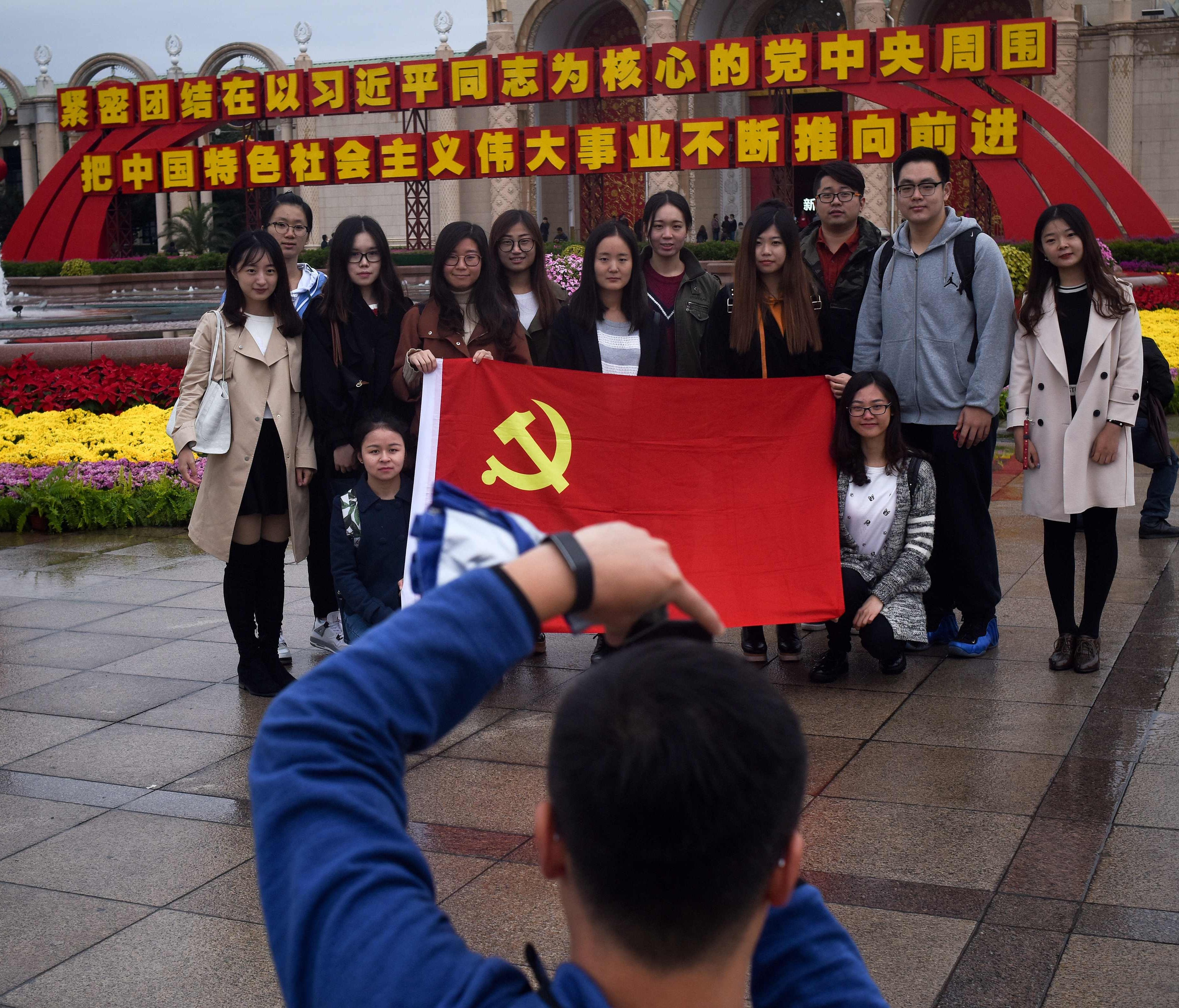 This picture taken on October 10, 2017 shows People take a group photo with a flag of the Chinese Communist Party during an exhibition showcasing China's progress in the past five years at the Beijing Exhibition Center, on Oct. 10, 2017.