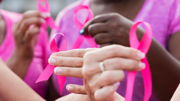 Medical workers hold pink breast cancer ribbons