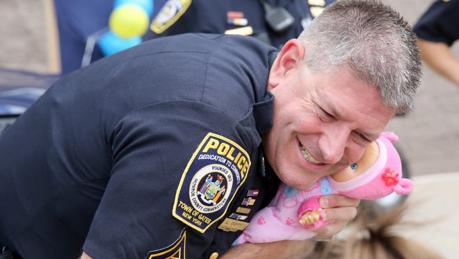Lance Duffy, with the Gates Police Department, gives a little girl's doll a hug in July 2016 at the Gates Walmart where officers came out to bond with the community.