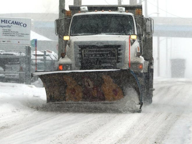 A snowplow begins to clear snow off the road on Masschusetts Avenue in Indianapolis as heavy snowfall limits visibility for drivers on Friday, February 14, 2014, resulting in many accidents on city streets and interstates.