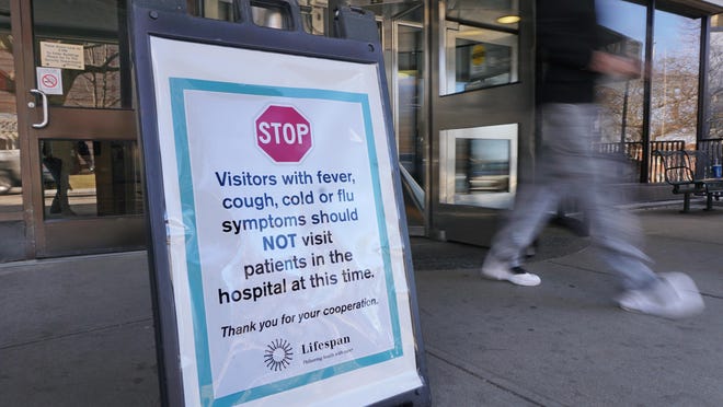 PROVIDENCE, RI -- A sign in front at the revolving door of the main entrance warns visitors from visiting if they have cold or flu symptoms. Preparations for coronavirus at Rhode Island Hospital. Signs around the hospital, and  supplies that they are assembling to be ready.