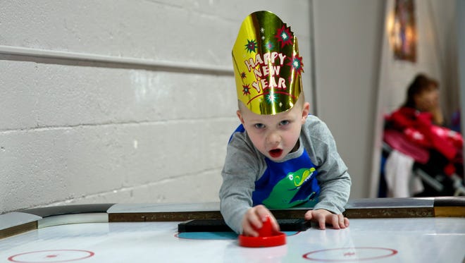 Dillon Wright, 3, plays air hockey on Saturday at Play Day in Farmington. The business organized a Noon Year’s Eve Party for children.