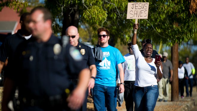 Chand Johnson holds a "Jesus Saves" sign as she chants "Peace, love, unity! In our community!" during a march down Martin Luther King Jr. Avenue on Saturday, Oct. 29, 2016. Knoxville community members and the Knoxville Police Department marched together in support of the efforts to bridge the gap between police and the community as well as to avoid violence and injustice.