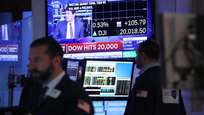 Traders work on the floor of the New York Stock Exchange as the Dow Jones Industrial Average crossed over the 20,000 mark for the first time after at the opening bell.