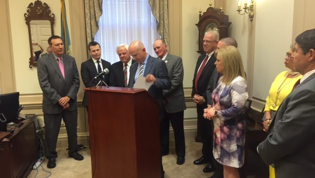 Surrounded by both Democratic and Republican lawmakers, Gov. Jack Markell signs an executive order aimed at reviewing regulations for professional licenses.